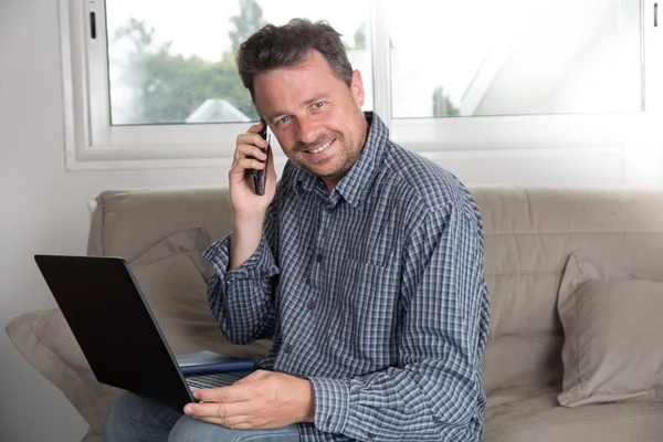 Uomo guardando e lavorando sul computer portatile a casa — Foto Stock