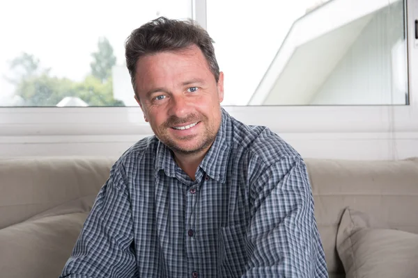 Glimlachende man van middelbare leeftijd, close-up in zijn woonkamer — Stockfoto