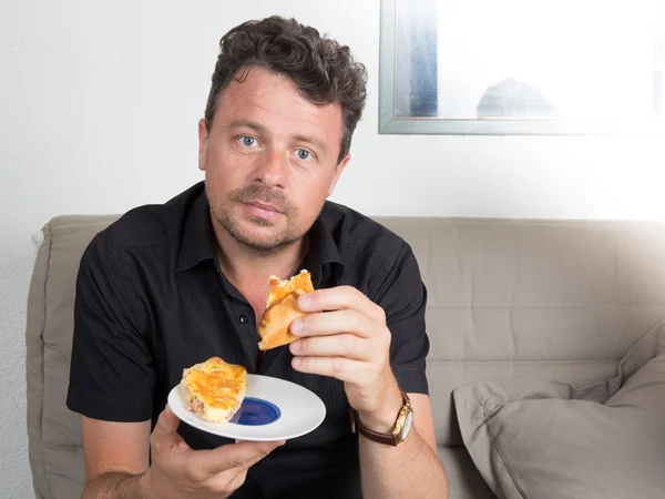 L'uomo sta mangiando davanti alla telecamera sul divano — Foto Stock