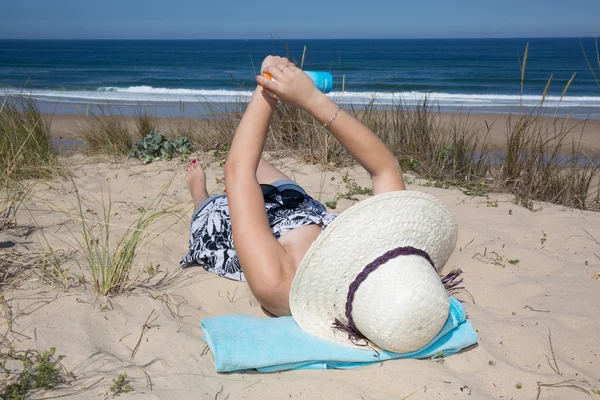 Protector solar mujer mostrando botella de loción bronceadora aplicando crema solar al brazo — Foto de Stock