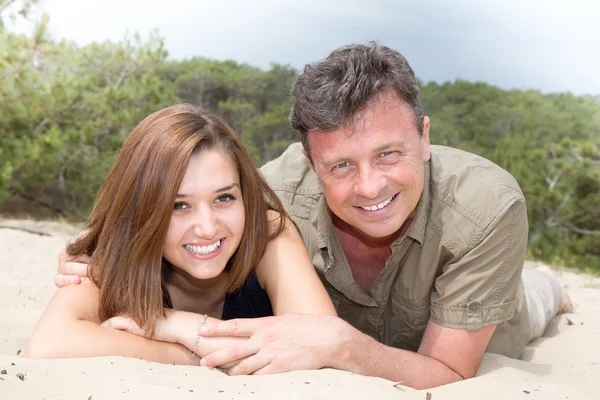 Cheerful couple having fun on seaside, on the sand grains — Stock Photo, Image