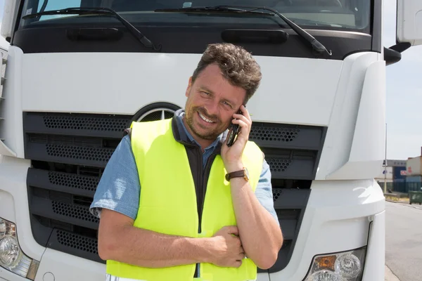 Prawdziwe robotnik za pomocą telefonu komórkowego, obok ciężarówki — Zdjęcie stockowe