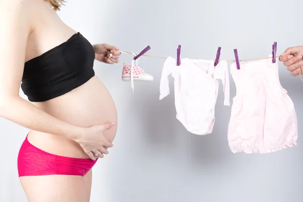 Gravid kvinna hängande barnkläder på rep — Stockfoto