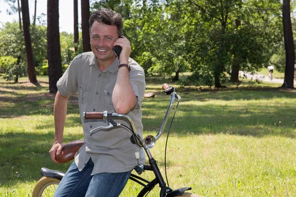 Man talar i mobiltelefon håller sin cykel. — Stockfoto