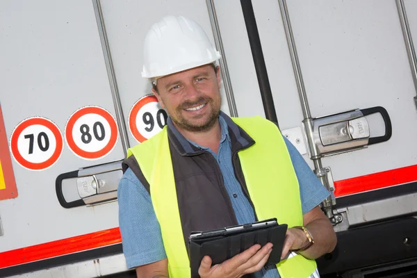 Knappe levering man die lacht met behulp van digitale tablet per vrachtwagen — Stockfoto