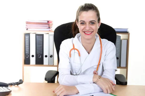 Jonge lachende dokter zitten aan de balie met armen gekruist — Stockfoto