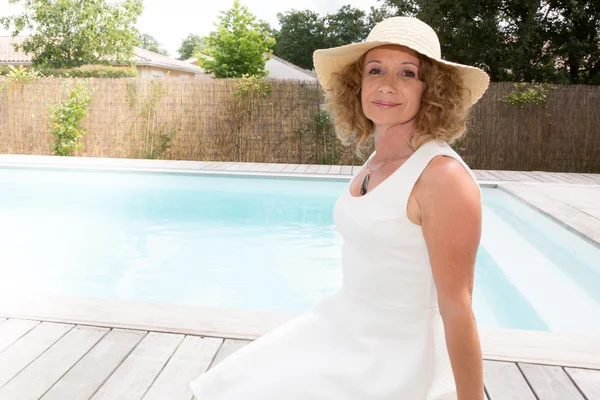Красива блондинка з капелюхом і біла сукня в басейн — стокове фото
