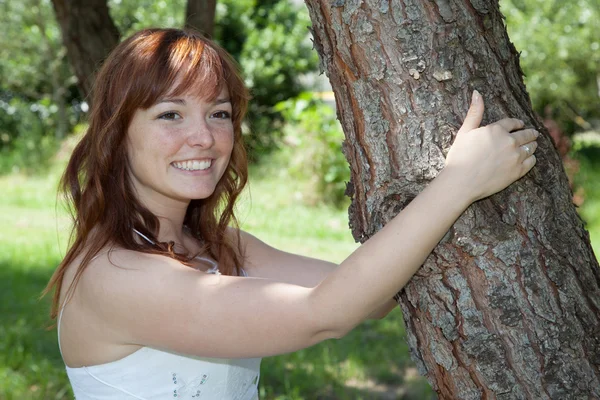 Braut mit roten Haaren im Brautkleid vor dem Baum — Stockfoto