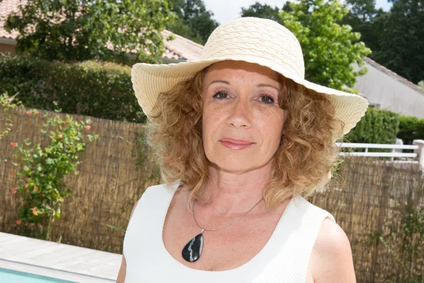 Femme sexy d'âge moyen dans la piscine avec un chapeau et une robe blanche — Photo