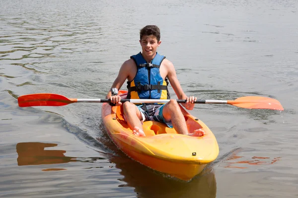 Felice giovane uomo remare sul lago in kayak e sorridente — Foto Stock