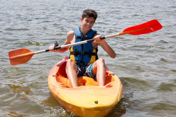 Happy young man rowing on lake in kayak and smiling — Stock Photo, Image