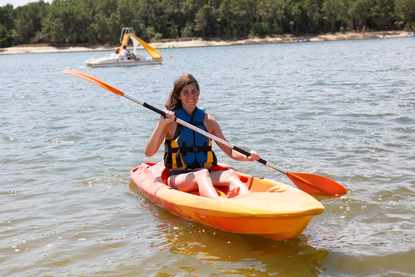 Fitte Frau rudert im Kajak auf See und lächelt — Stockfoto