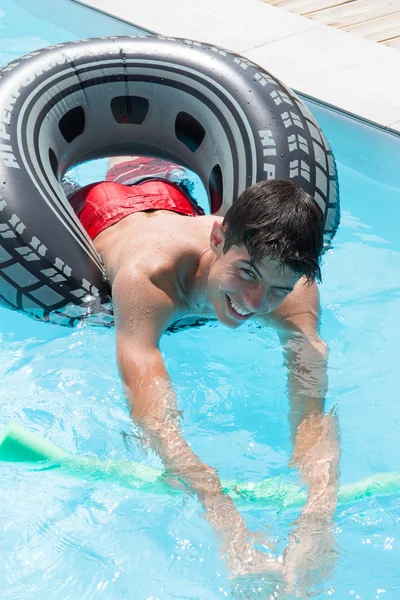 Gelukkig jonge man spelen op een boei in een pool — Stockfoto