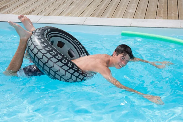 Gelukkig jonge man spelen op een boei in een pool — Stockfoto