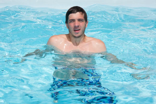 Lycklig attraktiv man i blå vatten i en pool — Stockfoto