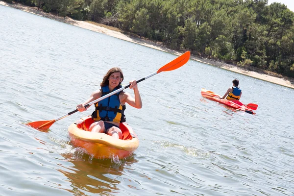 Joyeux et souriant femme d'âge moyen kayak sur un lac . — Photo