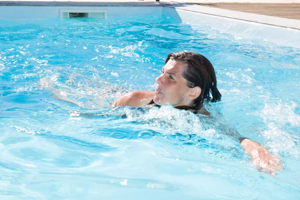 Kvinna med baddräkt simmar på en blå vatten pool — Stockfoto