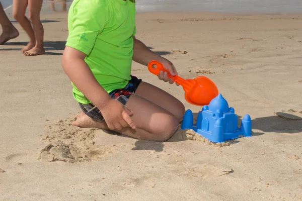 Boy with a green shirt playing with toys on beach — Stock Photo, Image