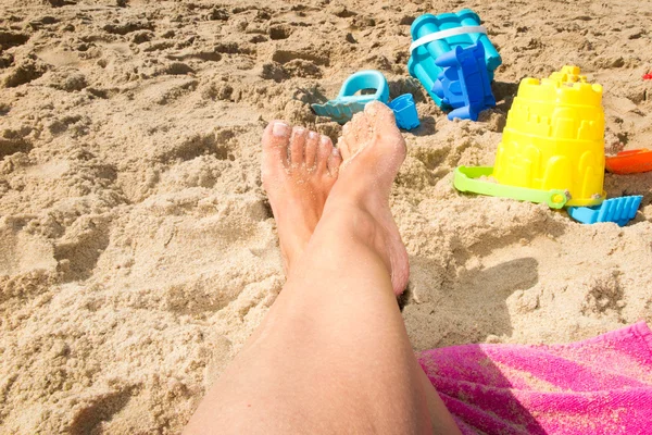 Girl legs on the beach with plastic bucket and spade — Stock Photo, Image