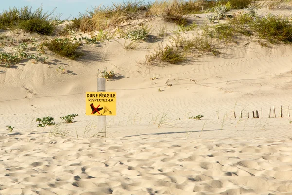 Strand duinen en houten piket omheining, met waarschuwing "Doen niet lopen op duinen"-teken in het Frans — Stockfoto