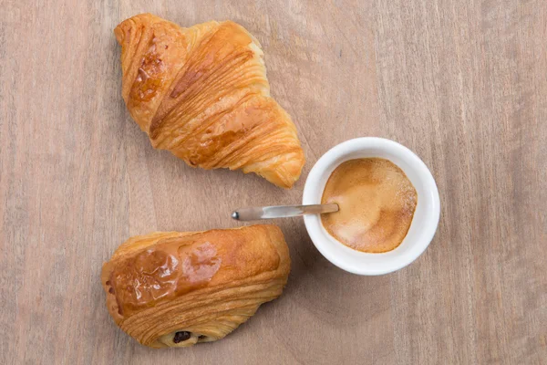 Croissants y café sobre un fondo de mesa de madera . — Foto de Stock