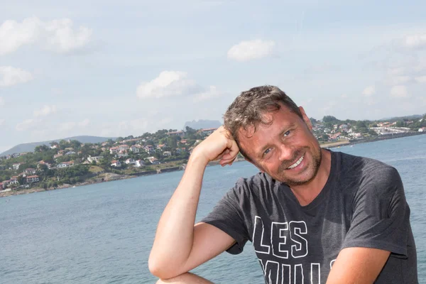 Bell'uomo vicino al mare sorridente alla macchina fotografica — Foto Stock