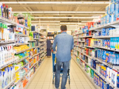 Alışveriş sepeti kadar dolu süpermarket koridorda iterek adam.