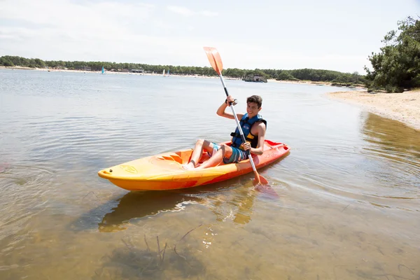 Kayak ragazzo sul fiume sotto il cielo blu — Foto Stock