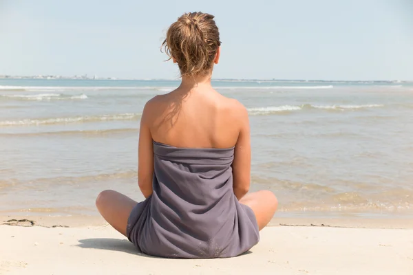 Ritratto di una bella giovane donna seduta in posa yoga in spiaggia — Foto Stock