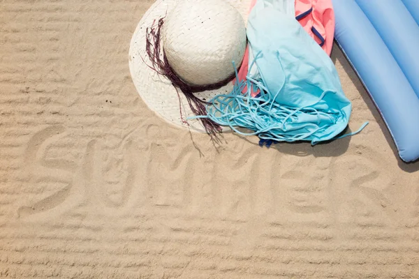 Chapéu e vestido, o verão está escrevendo na areia — Fotografia de Stock