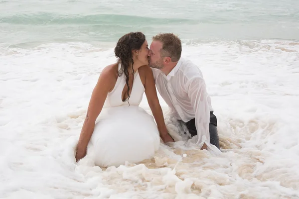 Romantisches frisch verheiratetes Paar. Junger Bräutigam küsst seine Braut im Meer — Stockfoto