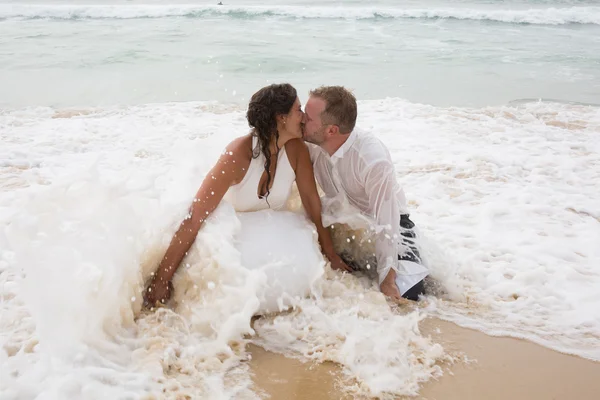 Romantisches frisch verheiratetes Paar. Junger Bräutigam küsst seine Braut im Meer — Stockfoto