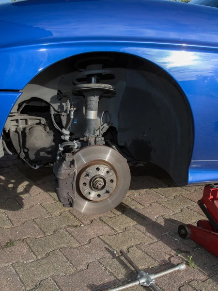 Mécanicien changer une roue d'une voiture bleue moderne — Photo