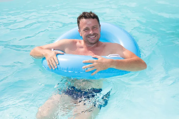 Uomo rilassante sulla boa d'aria in piscina. concetto di vacanza e tempo libero — Foto Stock