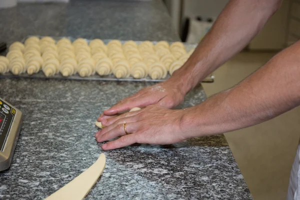 Baker haciendo croissants sobre fondo gris —  Fotos de Stock