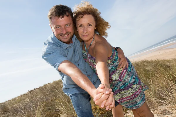 Счастливые мужчина и женщина держатся за руки на пустынном тропическом пляже — стоковое фото