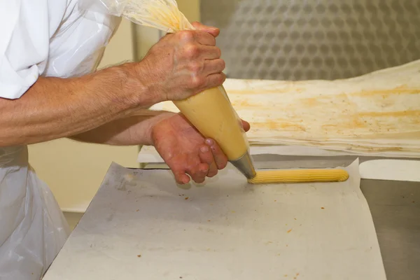 Baker hombre prepara pasteles y eclairs —  Fotos de Stock
