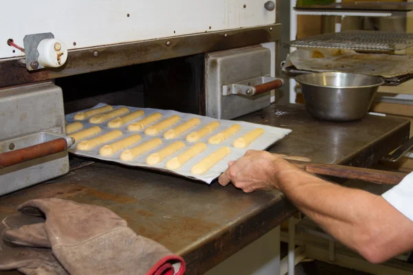 Producción de panadería. hombre, panadero, poner los pasteles en el horno —  Fotos de Stock