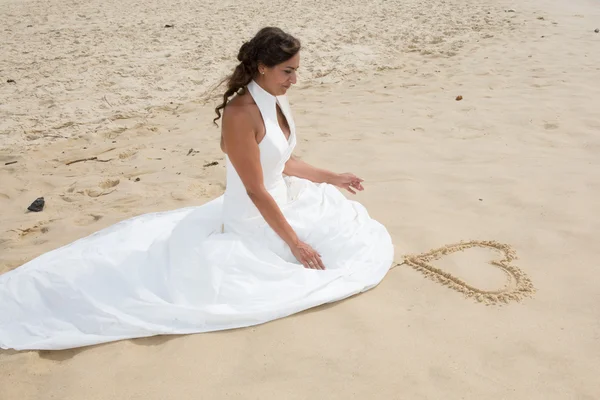 Newly married couple drawing connected hearts on the beach — Stock Photo, Image