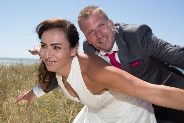 Happy bride and groom at the beach outside having fun — Stock Photo, Image