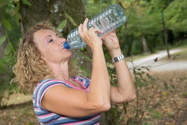 Portrait d'une femme blonde buvant de l'eau au parc vert d'été . — Photo