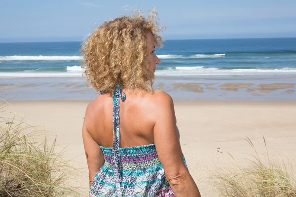 Felice bionda in piedi nel mare in posa in una giornata di sole — Foto Stock