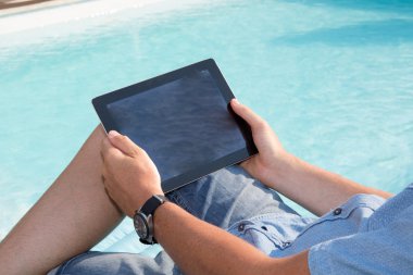 Dijital tablet ile havuz oturan adam