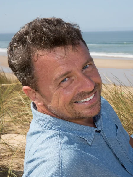 Happy handsome man smiling at the beach — Stock Photo, Image