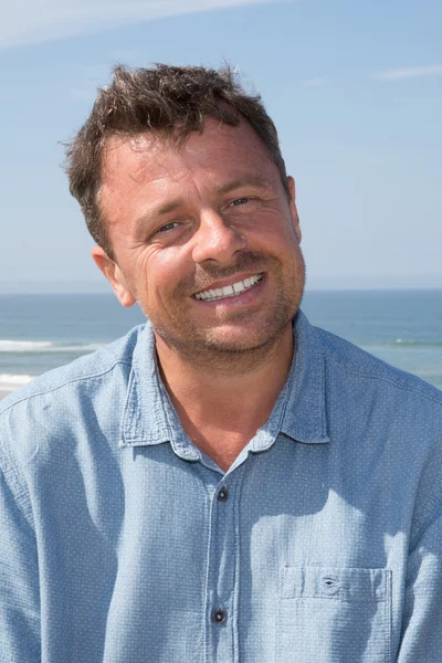 Gelukkig knap man die lacht op het strand — Stockfoto