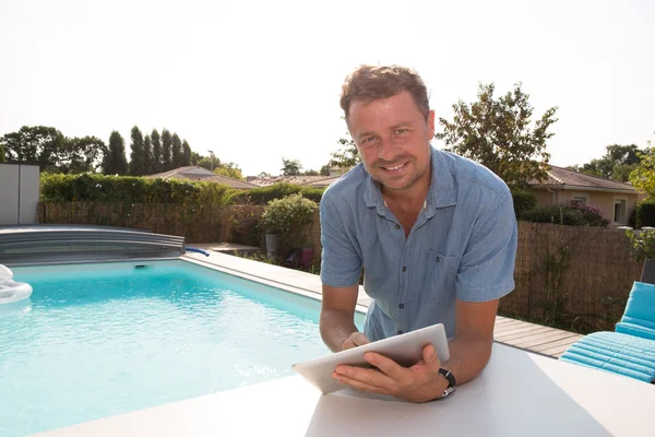 Uomo hispter in piedi vicino alla piscina sorridente con tablet digitale — Foto Stock