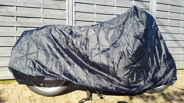 motorcycle protected by silver and blue bike protective cover in street motorbike with tarpaulin jacket