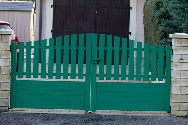 green modern house gate and garage door to access home garden