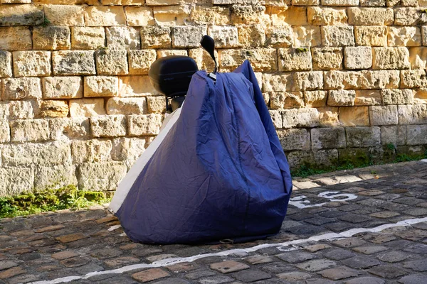 bike protected by modern blue motorcycle protective cover in street motorbike with tarpaulin jacket