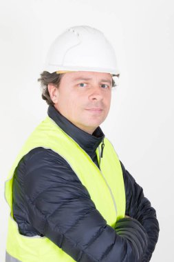 Kask kollu yakışıklı işçi beyaz arka planda sarı yelek giyiyor.